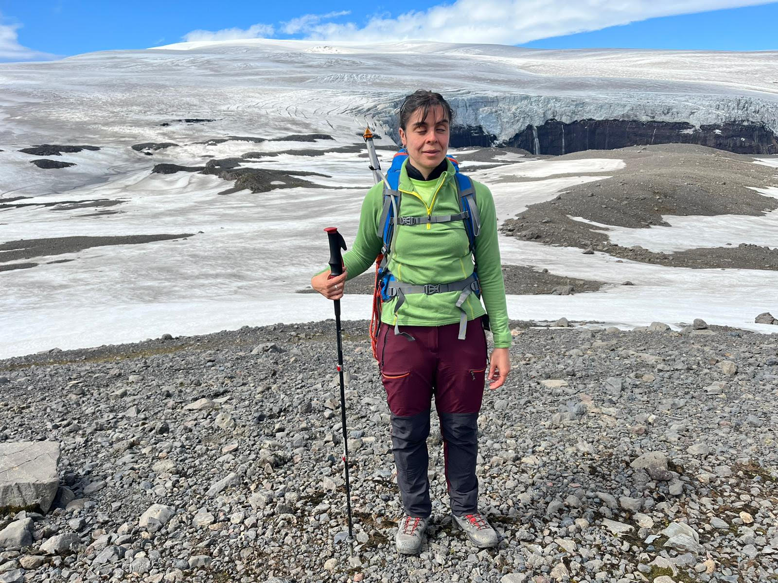 Descripción de la foto de portada: La foto está tomada en la cumbre del pico Sker, en tierras altas de Islandia. Erika está de pie y porta un bastón y su mochila. Tras ella, una espectacular vista del glaciar.