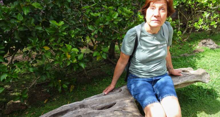 Descripción de la foto de portada: Margarita aparece a la derecha de la foto sentada sobre un tronco y con vegetación detrás. La foto fue tomada durante un viaje a Hawai.