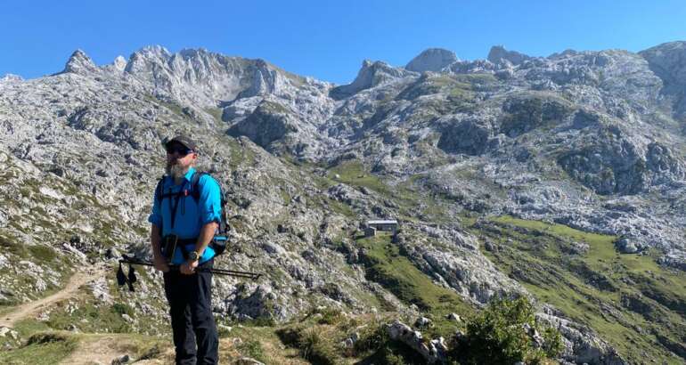 Descripción de foto de portada: El autor en el Macizo Occidental de Picos de Europa. Montañero con una vista de montañas y refugio al fondo.
