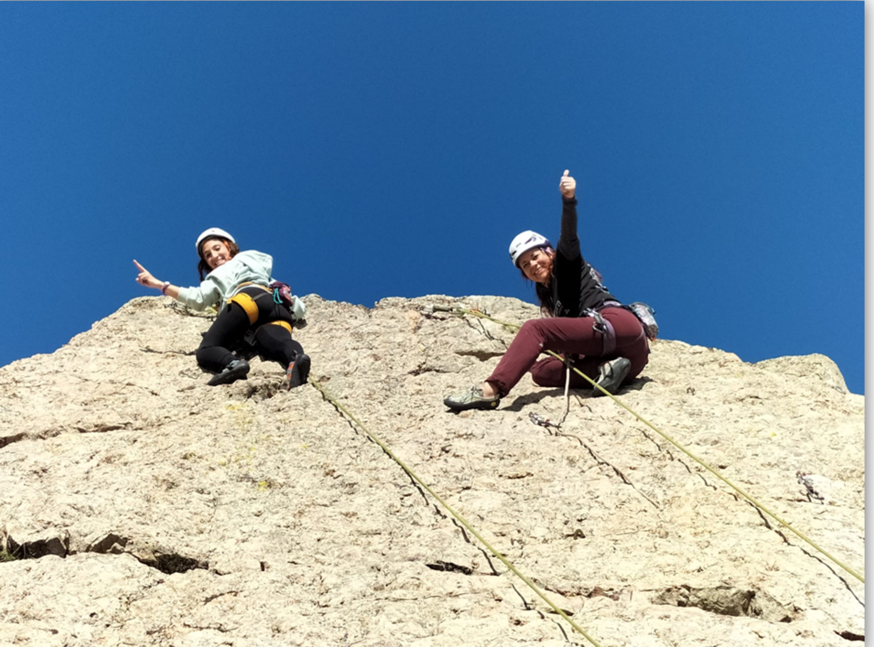 Sorprendemos a dos escaladoras muy sonrientes en el top de una vía de escalada en roca. Situadas junto a la reunión de la vía, nos indican con la mano levantada que han completado el ascenso. Esta pared de roca se encuentra situada en la provincia de Badajoz (Extremadura).