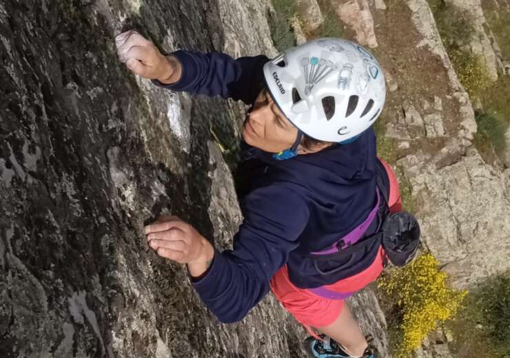 Almudena García aparece en primer plano escalando, con un casco blanco y una camiseta de manga larga azul, en la escuela de escalada que está en el El Castellar, junto a su casa, en su cara se refleja el esfuerzo y el disfrute al mismo tiempo, al fondo un patio espectacular de varios metros.