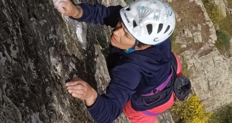 Almudena García aparece en primer plano escalando, con un casco blanco y una camiseta de manga larga azul, en la escuela de escalada que está en el El Castellar, junto a su casa, en su cara se refleja el esfuerzo y el disfrute al mismo tiempo, al fondo un patio espectacular de varios metros.