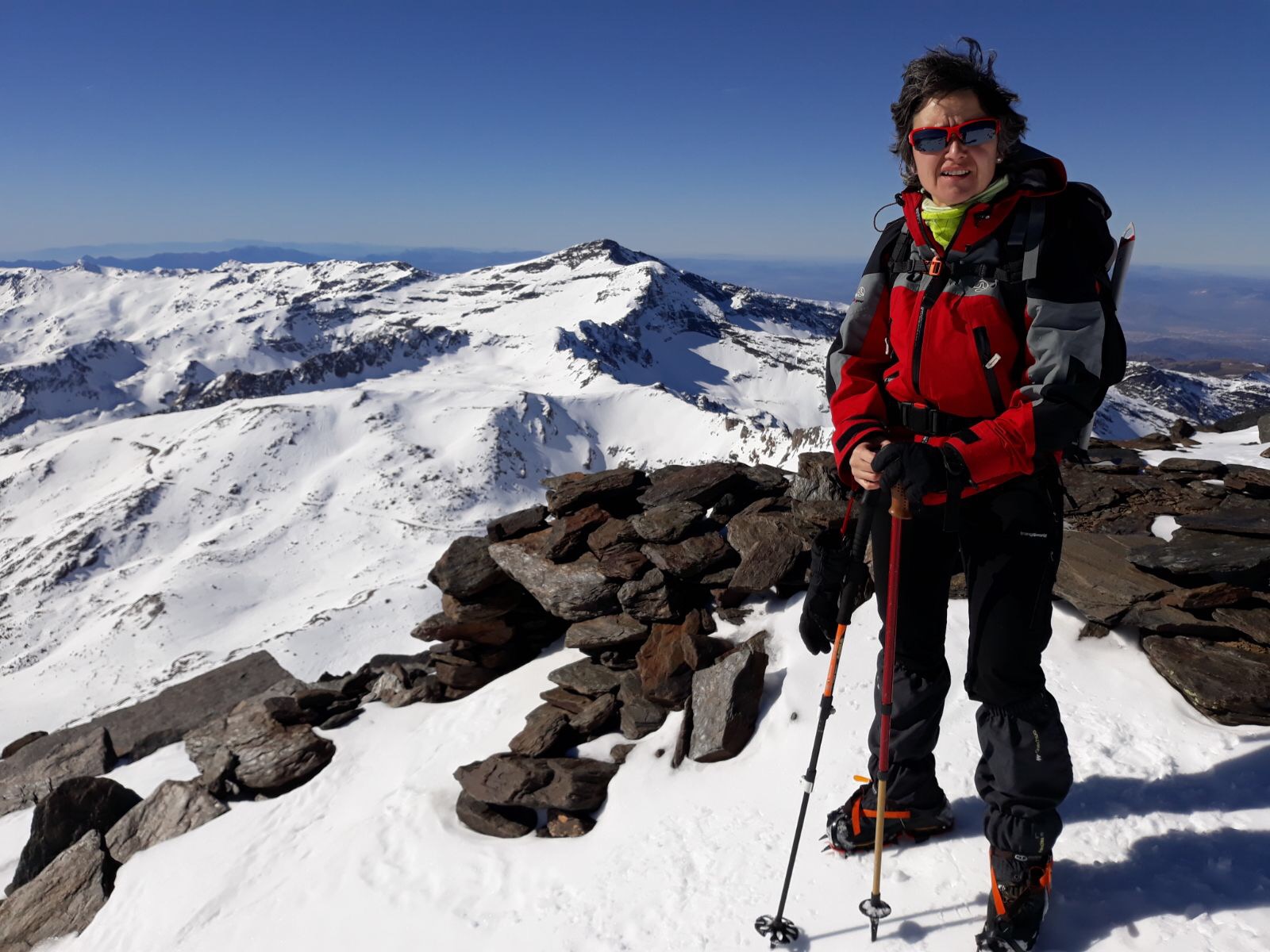 Laura está en la cima del Mulhacén, en Sierra Nevada. A su alrededor amplias vistas de este macizo montañoso completamente nevado.